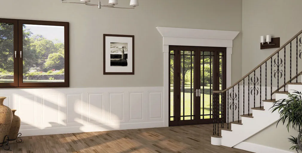 White raised panel half wall paneling in entryway with wood staircase and warm gray walls