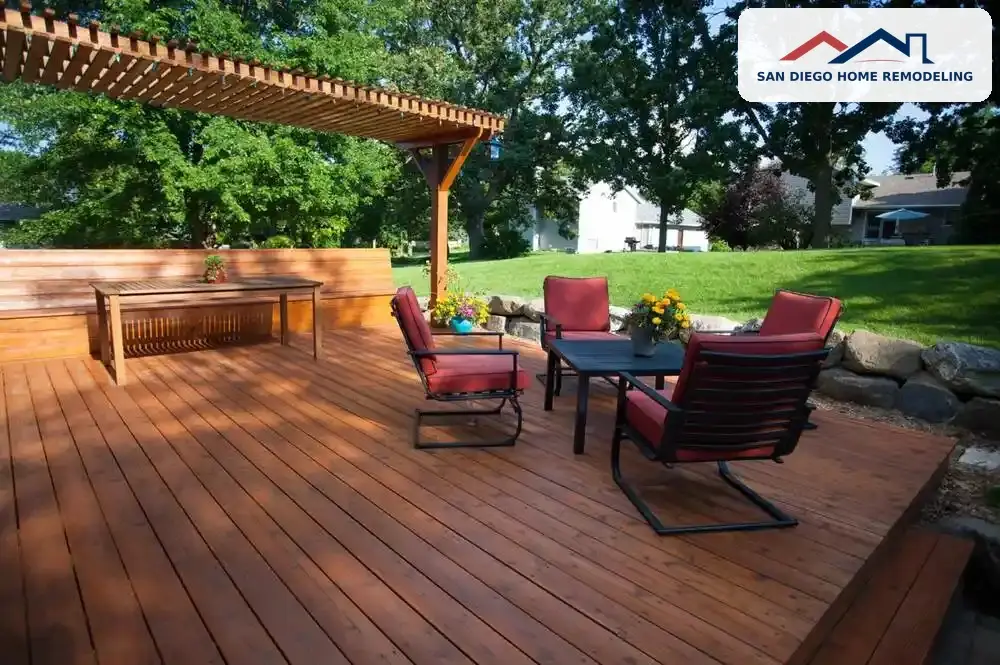 Backyard wooden floating deck with pergola, red cushioned outdoor seating, and coffee table, San Diego Home Remodeling