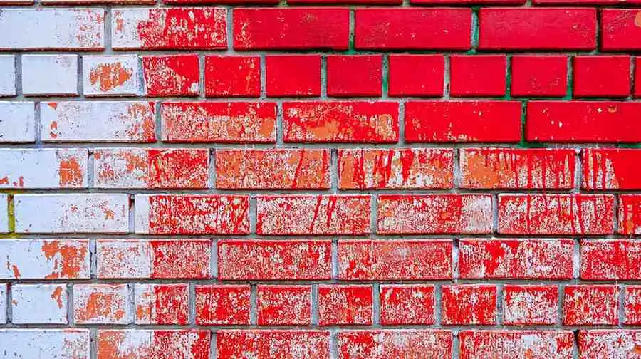 how to remove paint from brick showing partially stripped red paint revealing natural brick underneath