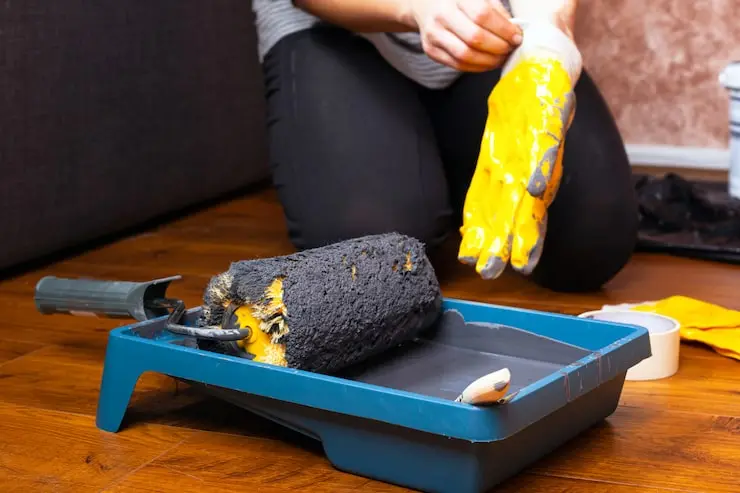 Homeowner showing how to clean paint rollers using warm soapy water and a bucket in a bright home setting for smooth, professional painting results.Learn How to Clean Paint Rollers in minutes with our step-by-step guide. Works for latex & oil-based paint. Reuse rollers 3-4 times and save money!