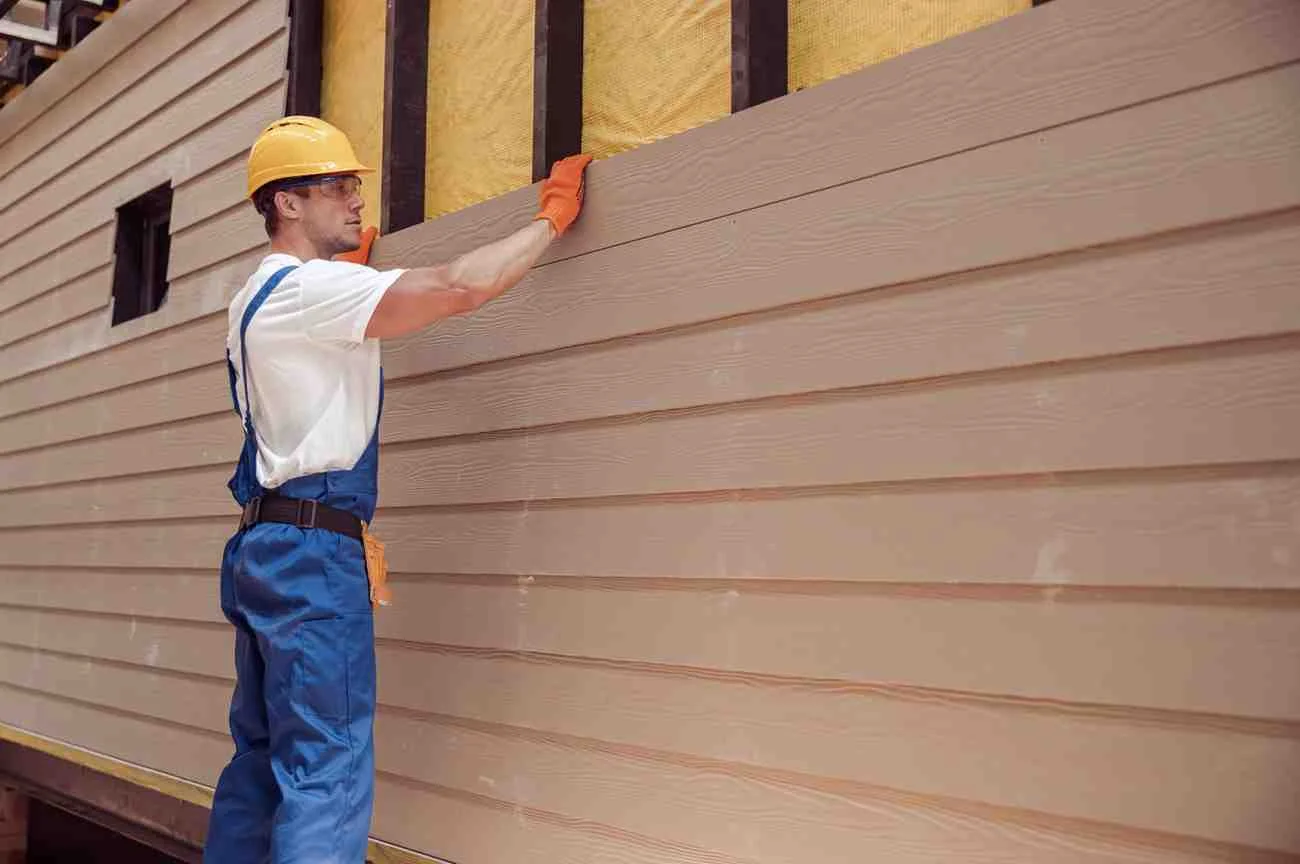 Benefits to Replacing Your Home’s Siding. Contractor installing new vinyl siding on a house to improve curb appeal, energy efficiency, and exterior protection