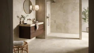 Curbless walk-in shower and dark walnut floating vanity in a 2026 trend bathroom with limestone tile and brass fixtures.