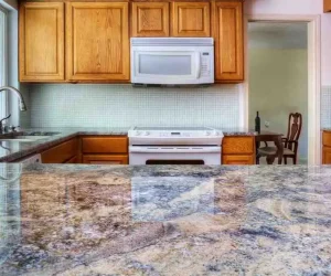 Countertop Installation Cost: Polished granite countertop with blue and beige veining installed in a kitchen with oak cabinets and tile backsplash, showing countertop installation cost quality
