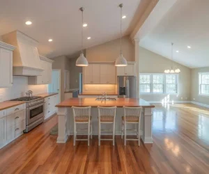 Raised Ranch Open Concept Kitchen featuring white shaker cabinets, butcher block island with seating, hardwood floors, and pendant lighting open to living area